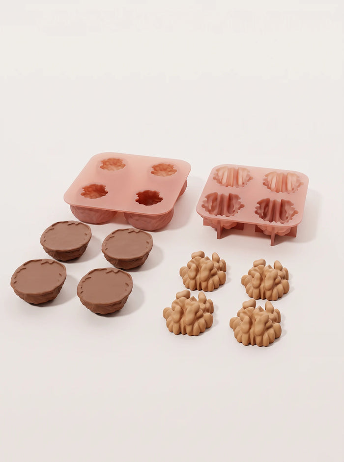 Separate brown shell-shaped cake bases and tan kernel-shaped cake tops, arranged below pink shell and kernel molds.