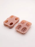 Two pink molds seen at an angle, with four oval openings in the shell mold on the left and four deeply textured kernel cavities on the right.