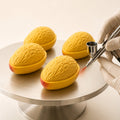Golden Mango mousse cake receiving a red velvet spray finish for a realistic fruit texture