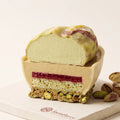 Cut pistachio mousse cake revealing layered mousse, filling, cake and crunchy base